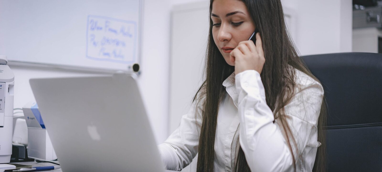 Vrouw aan telefoon achter laptop